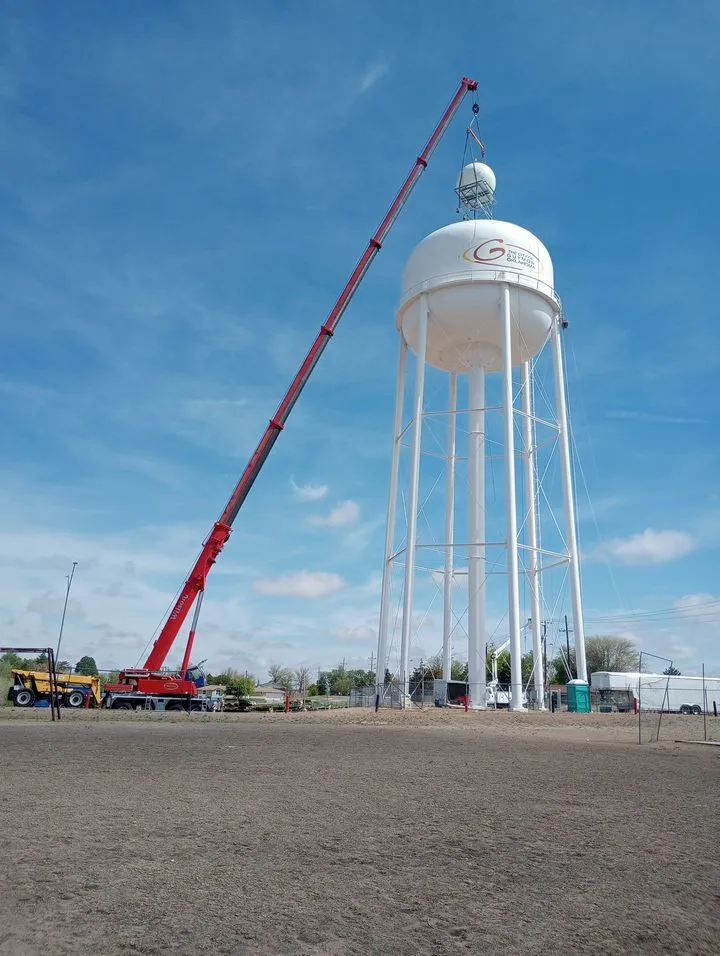 Crane working alongside a newly finished municipal water tower