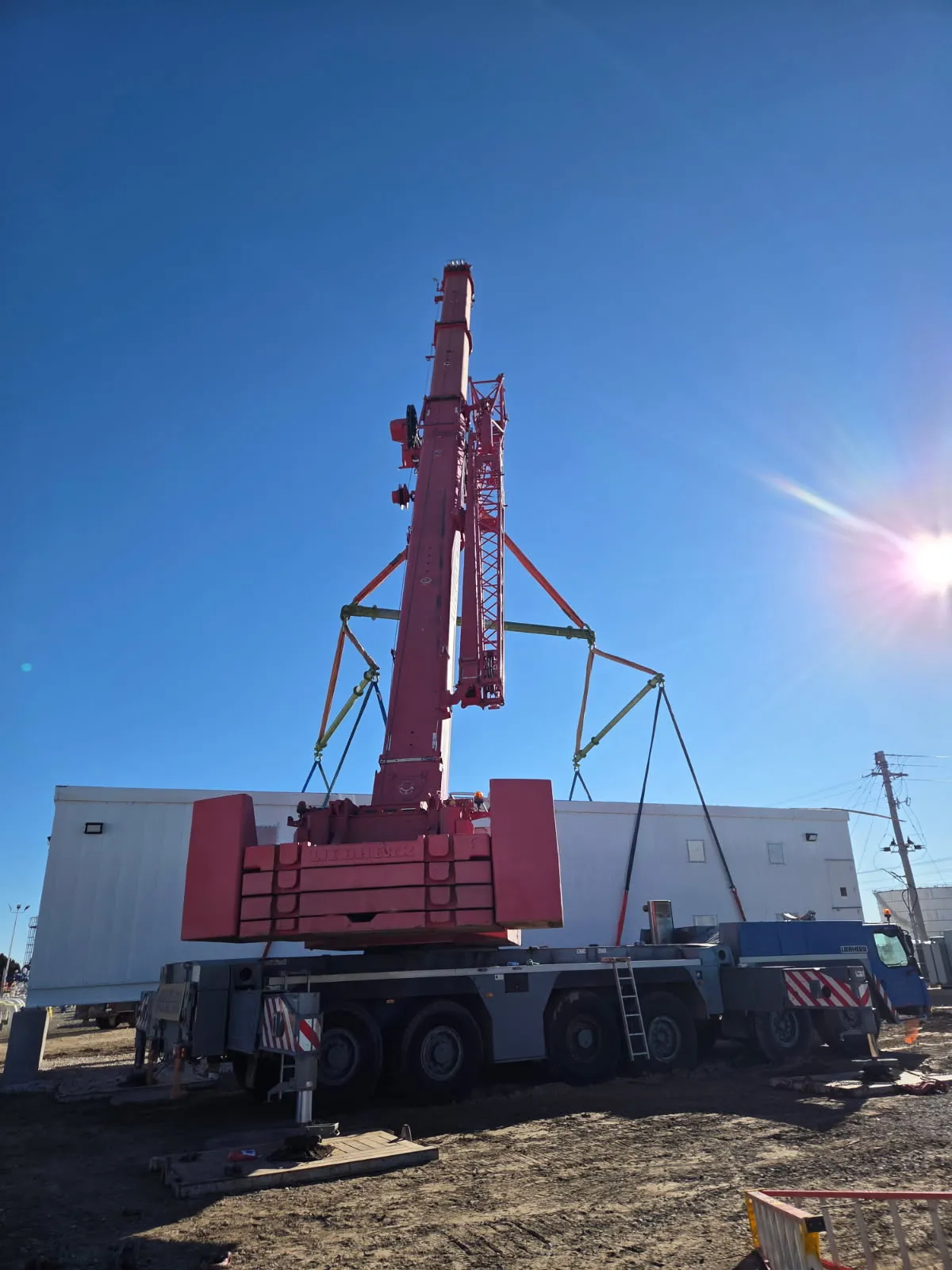 Liebherr all-terrain crane rigged with a lifting frame, boom raised at an industrial site